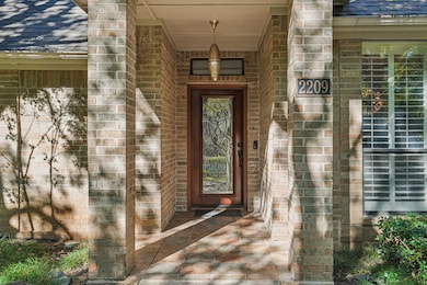Property entrance featuring a shingled roof and brick siding