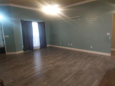 Unfurnished room with baseboards, a brick fireplace, and wood finished floors