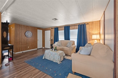 Living area with wood finished floors, wood walls, and a textured ceiling