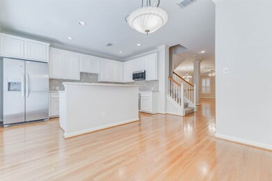 This bright kitchen features classic white cabinetry, granite countertops, under-cabinet lighting, and stainless steel appliances—including a French door fridge and built-in microwave. The breakfast nook is filled with natural light and connects effortlessly to the main living area. A breakfast bar and recessed lighting add form and function to this modern culinary space.