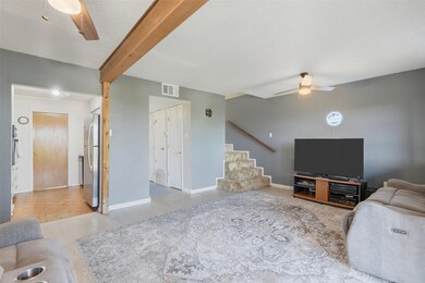 Living room with ceiling fan, beamed ceiling, light wood-type flooring, and a textured ceiling