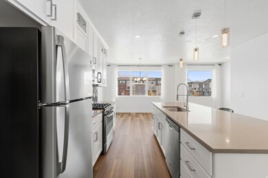 Kitchen with white cabinets, appliances with stainless steel finishes, pendant lighting, glass insert cabinets, and dark wood-style floors