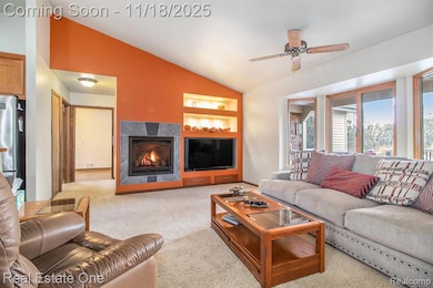 Living room featuring a tile fireplace, built in shelves, vaulted ceiling and ceiling fan