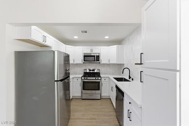 Kitchen featuring appliances with stainless steel finishes, backsplash, white cabinets, recessed lighting, and light wood-style floors