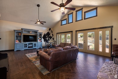Walking into Living room. Textured ceiling, high vaulted ceiling, healthy amount of natural light, a ceiling fan, and 2 French doors.