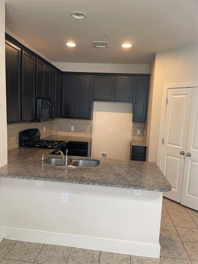 Kitchen with dark stone counters, a sink, a penin