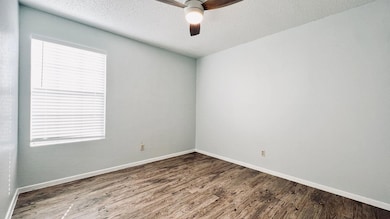 Empty room featuring wood finished floors, a textured ceiling, and a ceiling fan