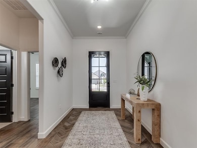 Foyer featuring baseboards, crown molding, and parquet floors