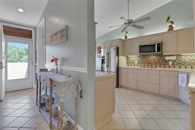 Kitchen featuring light tile patterned floors, backsplash, stainless steel appliances, a ceiling fan, and light brown cabinets