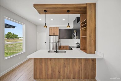 Kitchen with a sink, light countertops, stainless steel appliances, baseboards, and a peninsula