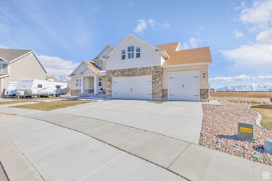 View of front facade with concrete driveway, a mountain view, board and batten siding, and stone siding
