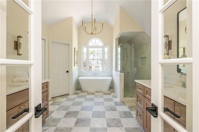 Bathroom with vanity, a soaking tub, a stall shower, vaulted ceiling, and a chandelier