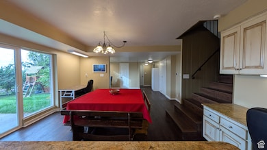 Dining area with dark wood-style flooring, stairs, a textured ceiling, and a chandelier