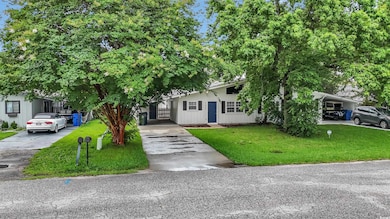 View of property hidden behind natural elements featuring concrete driveway and a front yard