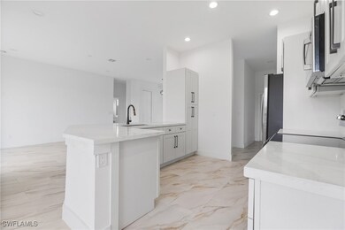 Kitchen with a sink, light stone counters, stainle