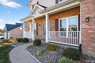 View of exterior entry with brick siding and covered porch