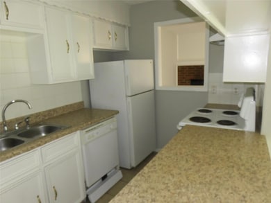 Kitchen featuring white cabinets, backsplash, white appliances, and sink