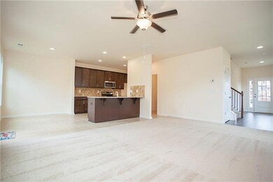 Kitchen featuring open floor plan, a breakfast bar, dark brown cabinets, backsplash, and recessed lighting