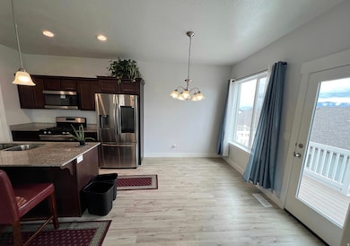 Kitchen featuring a breakfast bar area, stainless steel appliances, dark stone countertops, dark brown cabinets, and light wood-style floors