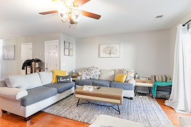 Living room featuring ceiling fan and light wood-t