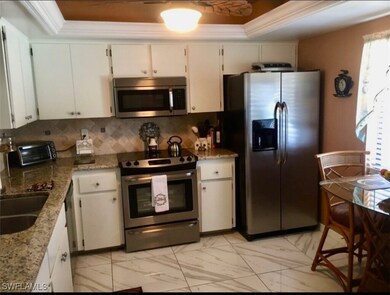 Kitchen featuring white cabinetry, a raised ceilin
