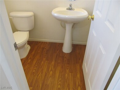 Half bathroom with wood finished floors, toilet, a