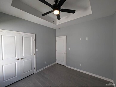 Empty room featuring dark hardwood / wood-style flooring, a tray ceiling, and ceiling fan
