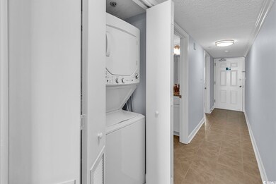 Laundry area featuring a textured ceiling, stacked