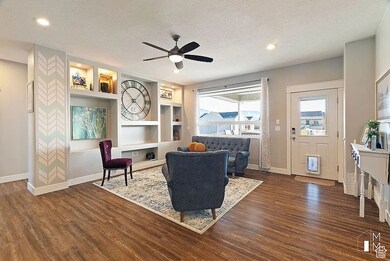 Sitting room with built in shelves, a textured ceiling, a ceiling fan, healthy amount of natural light, and dark wood-style flooring