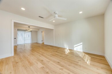 Empty room featuring light wood-type flooring and ceiling fan with notable chandelier