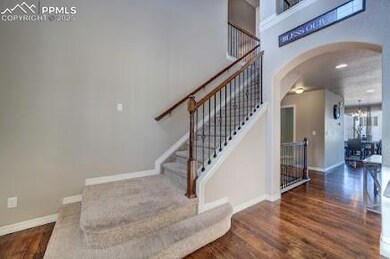 Stairs with baseboards, arched walkways, an inviting chandelier, and wood finished floors