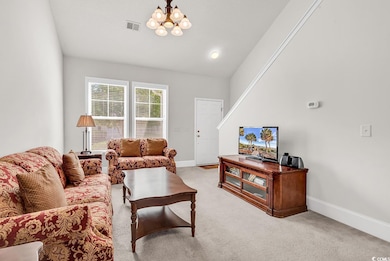 Living area with baseboards, light carpet, a chandelier, and vaulted ceiling