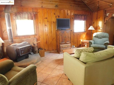 Tiled living room with lofted ceiling, wood walls, and wooden ceiling