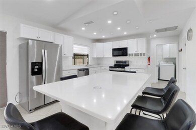 Kitchen with washer / clothes dryer, a breakfast bar, white cabinets, and appliances with stainless steel finishes