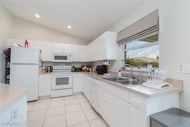 Kitchen featuring white appliances, a sink, light
