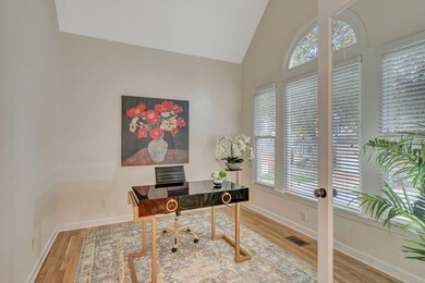 the office sits at the front of the home with a beautiful tree outside the large bank of windows