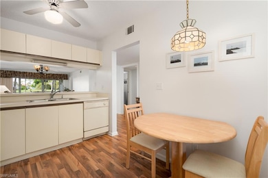 Kitchen with light countertops, hanging light fixtures, light wood finished floors, dishwasher, and cream cabinets