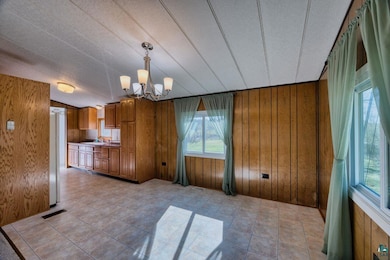 Kitchen with brown cabinetry, wooden walls, a chan