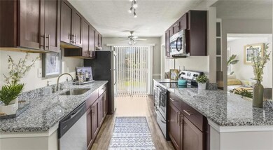 Kitchen featuring track lighting, stainless steel appliances, sink, a textured ceiling, and ceiling fan