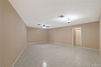 Empty room featuring ceiling fan, baseboards, visible vents, and light tile patterned floors