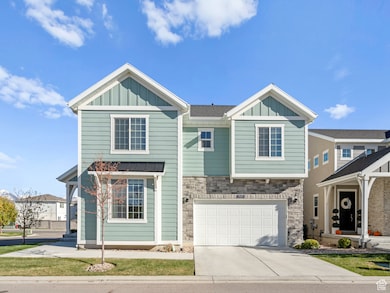View of front facade featuring board and batten siding, stone siding, driveway, and a garage