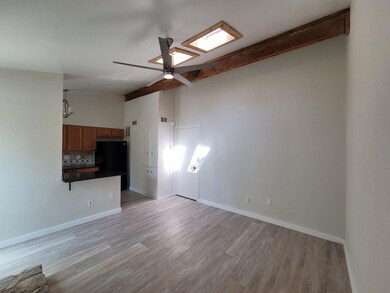 Unfurnished living room featuring beam ceiling, light wood-style flooring, ceiling fan, and high vaulted ceiling