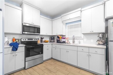 Kitchen featuring stainless steel appliances, a sink, light countertops, light wood-style flooring, and tasteful backsplash