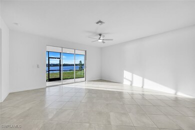 Empty room featuring a water view, ceiling fan, and light tile patterned floors