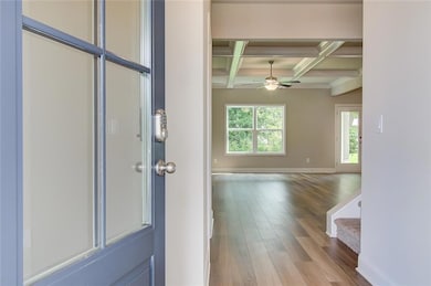 Entrance foyer featuring wood finished floors, beamed ceiling, a ceiling fan, coffered ceiling, and baseboards