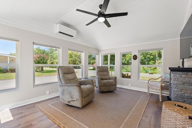Sunroom featuring lofted ceiling, wood finished floors, and an AC wall unit