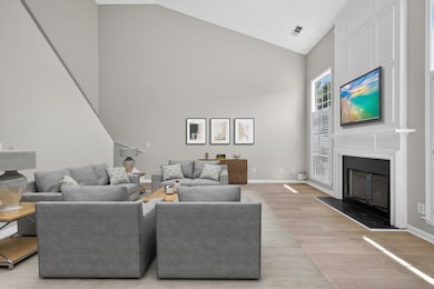 Virtually Staged Living area featuring high vaulted ceiling, light wood-style floors, and a large fireplace