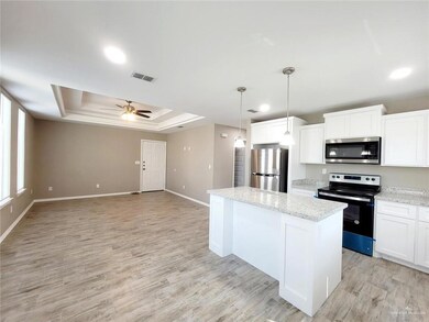 Kitchen with appliances with stainless steel finishes, a raised ceiling, a center island, open floor plan, and white cabinets