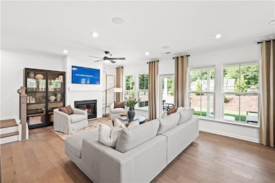 Living room with a fireplace, light wood-style flooring, a ceiling fan, and recessed lighting