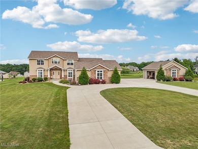 View of front of property featuring curved driveway, a front lawn, a garage, and stone siding